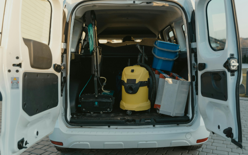 Car washing equipment including vacuum cleaner, buckets, and tools stored in the back of a van