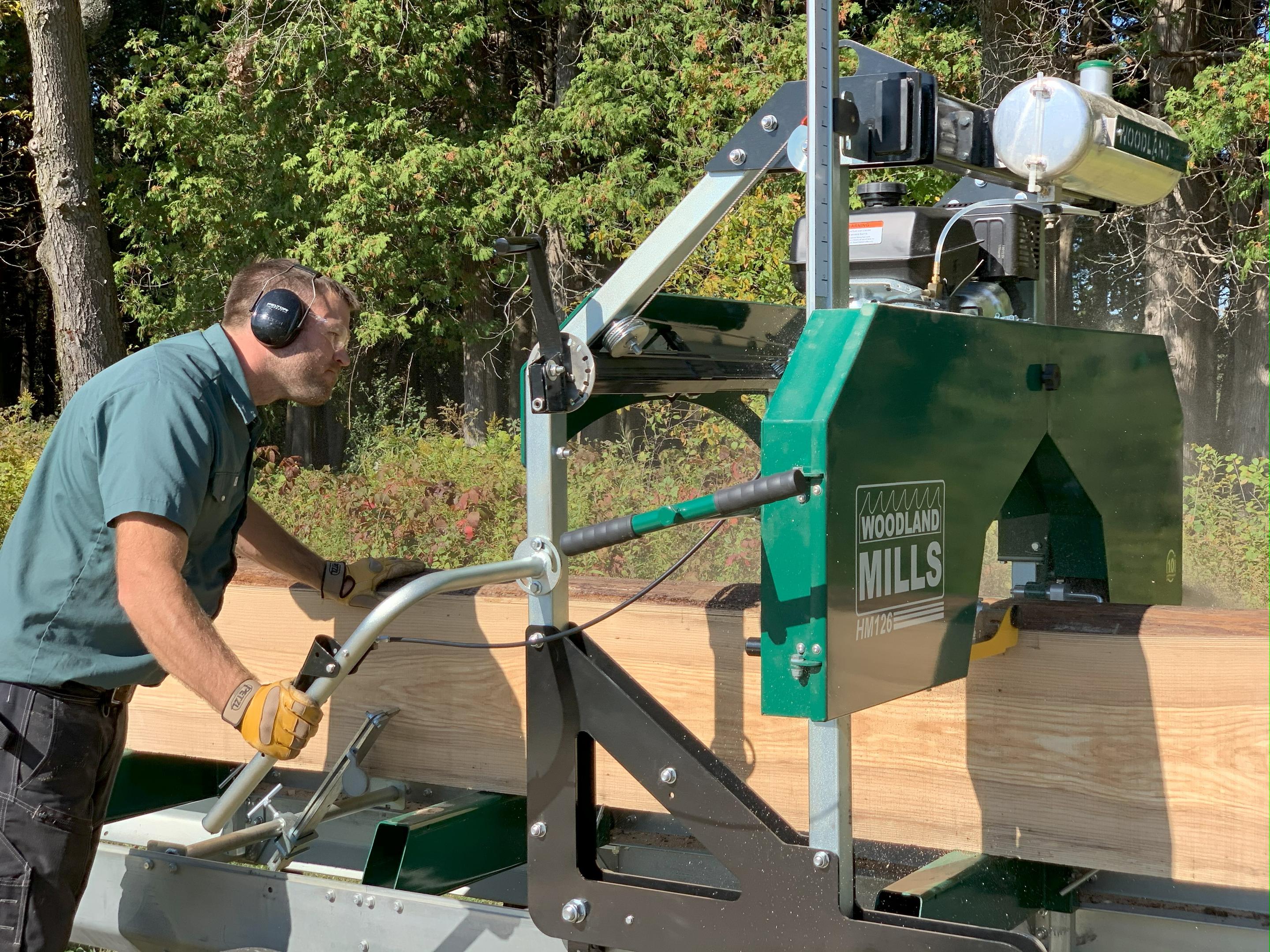 A man milling lumber on a Woodland Mills HM126 Portable Sawmill.