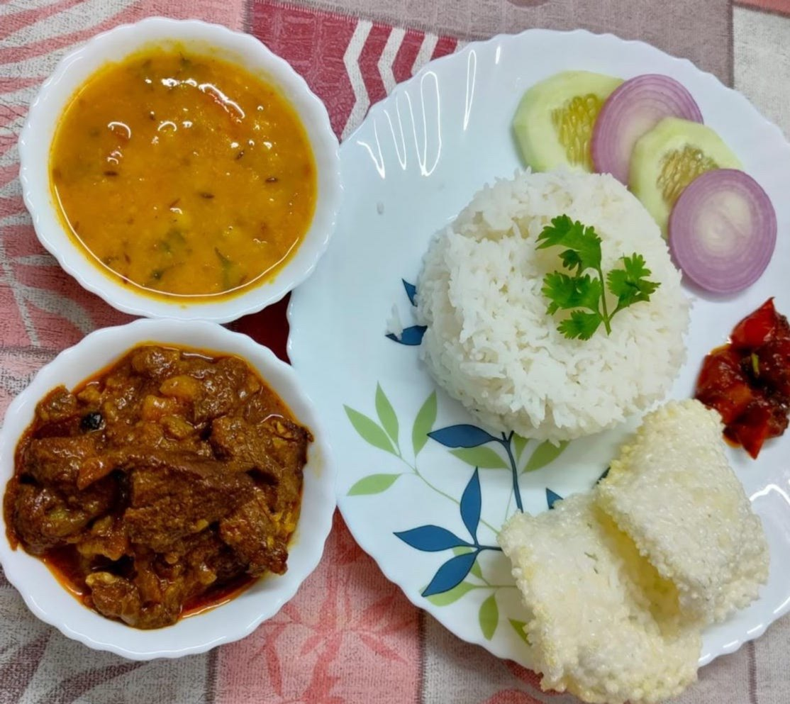 Mutton pickle with lentil daal, white rice, cucumber, onion slices, and crispy papadum.