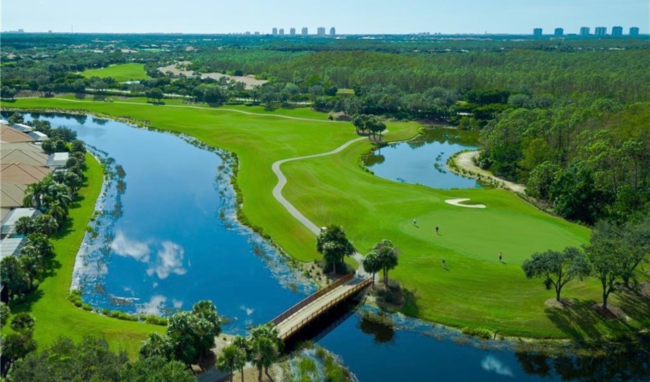 The image showcases a luxurious estate home with expansive views of a championship golf course, featuring resort-style outdoor living areas complete with a spacious screened lanai and a gas heated pool. This stunning custom estate home is situated in the desirable Shadow Wood community, offering an exceptional lifestyle amidst world-class amenities.