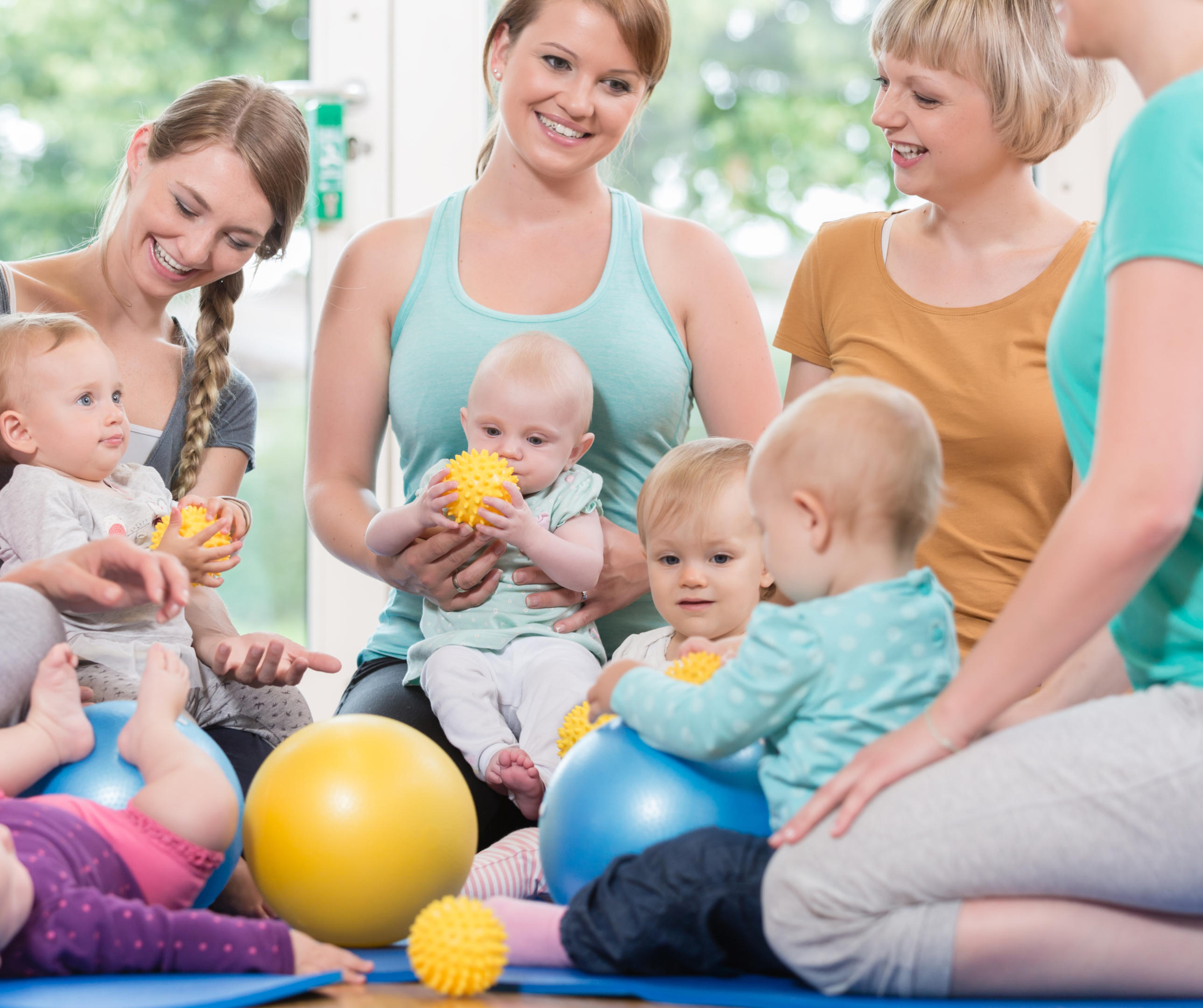 Eine Gruppe von Frauen sitzt im Kreis mit ihren Babys beim Rückbildungskurs.