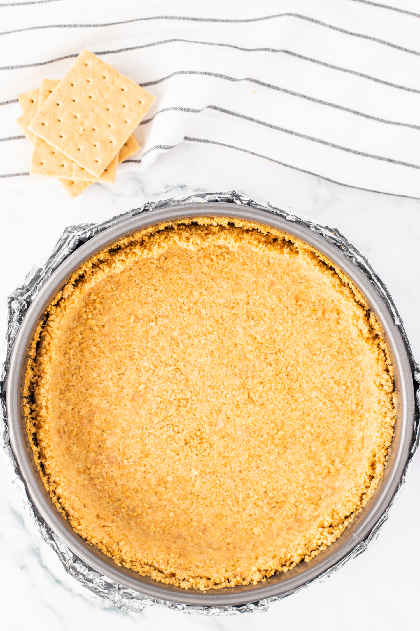 baked graham cracker crust in springform pan wrapped in tinfoil