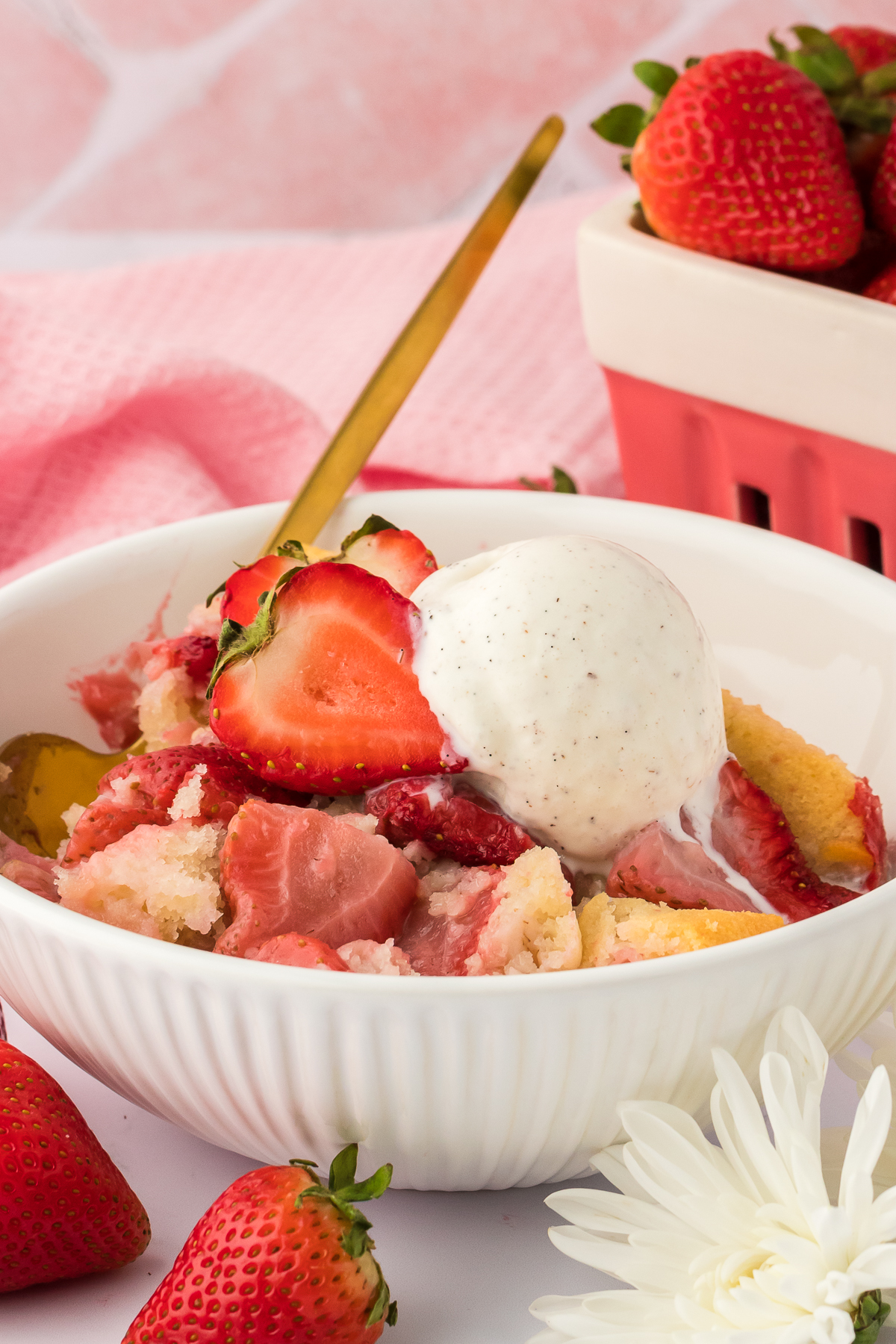 bowl of strawberry cobbler in bowl topped with vanilla ice cream 