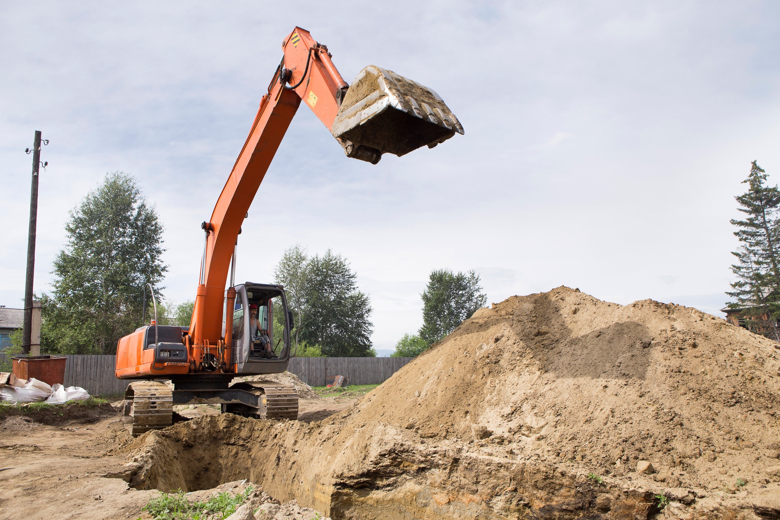 A worker uses construction site machinery without proper training to dig dirt