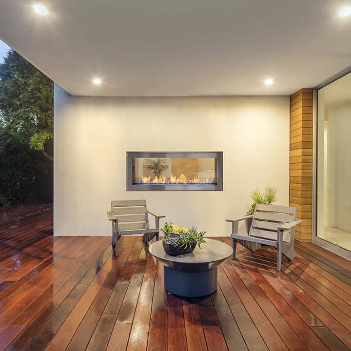 Double duty outdoor fireplace with a stone wall and a wooden bench