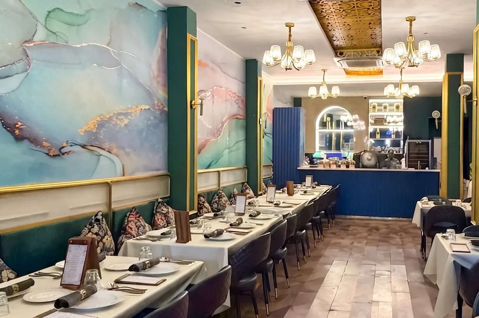 Elegant dining area at Restaurant Espoir featuring stylish marble walls, gold accents, and set tables.