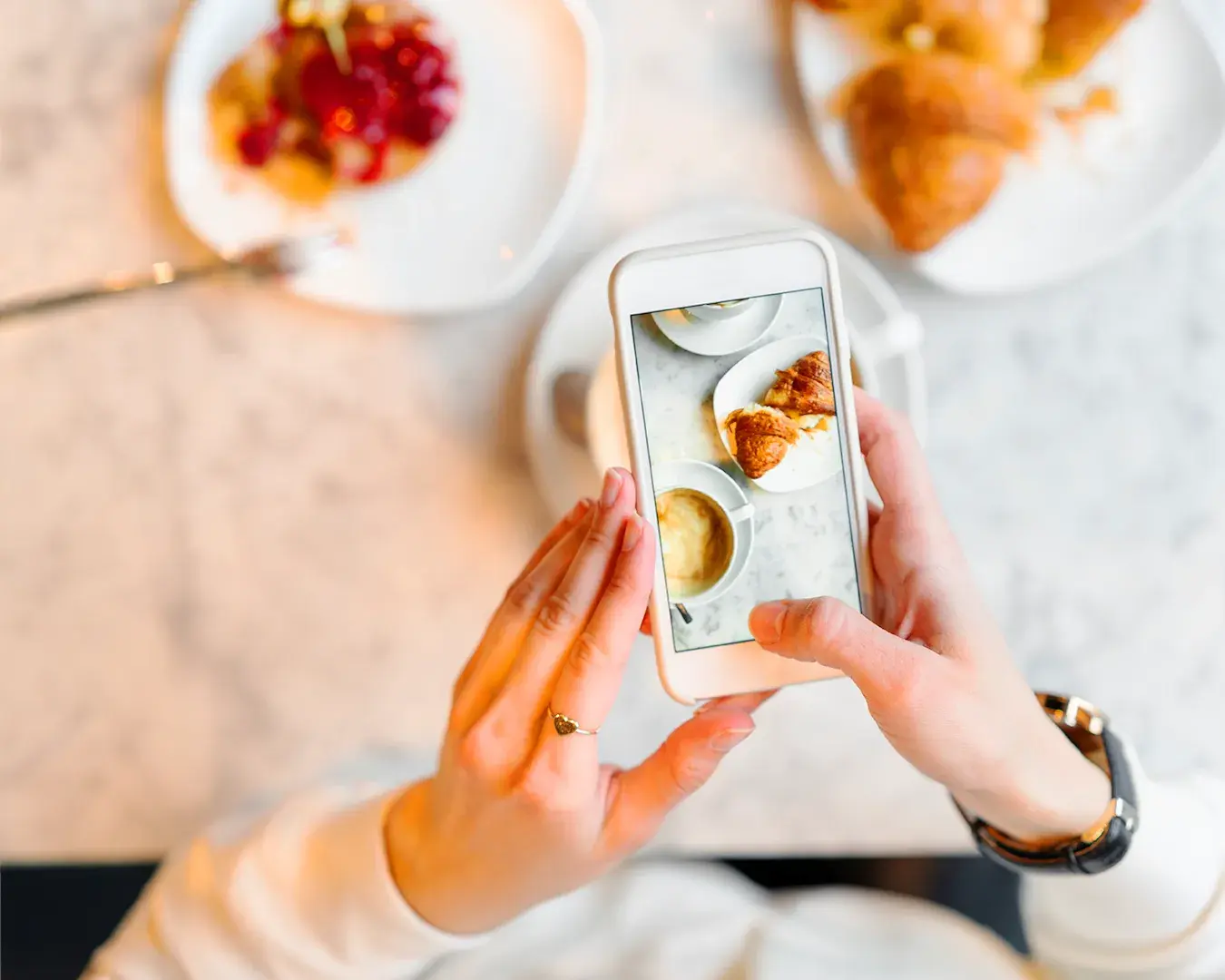 Customer photographing café breakfast with smartphone for social sharing and food discovery in Singapore restaurant marketing