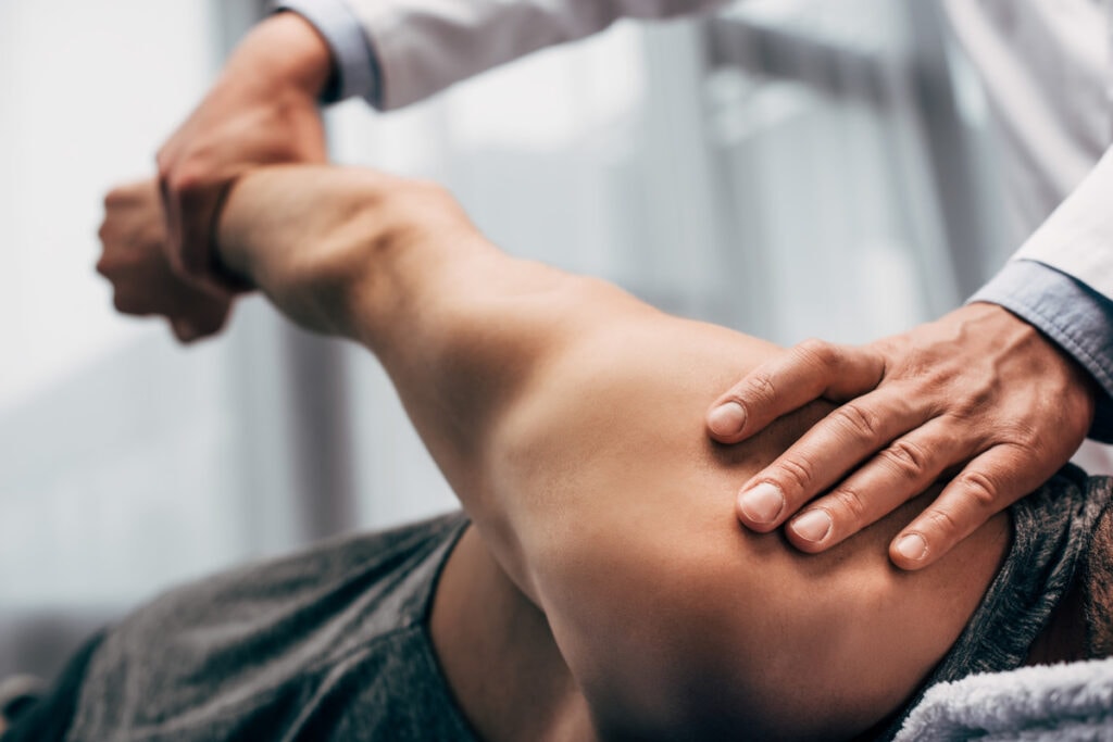 Physical therapist mobilizing a patient’s elbow and forearm during a manual therapy session.