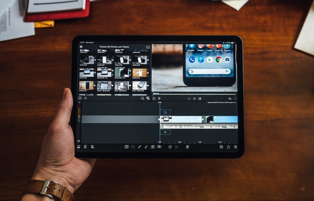 person holding a tablet with a video editing app showing a timeline of clips and editing tool