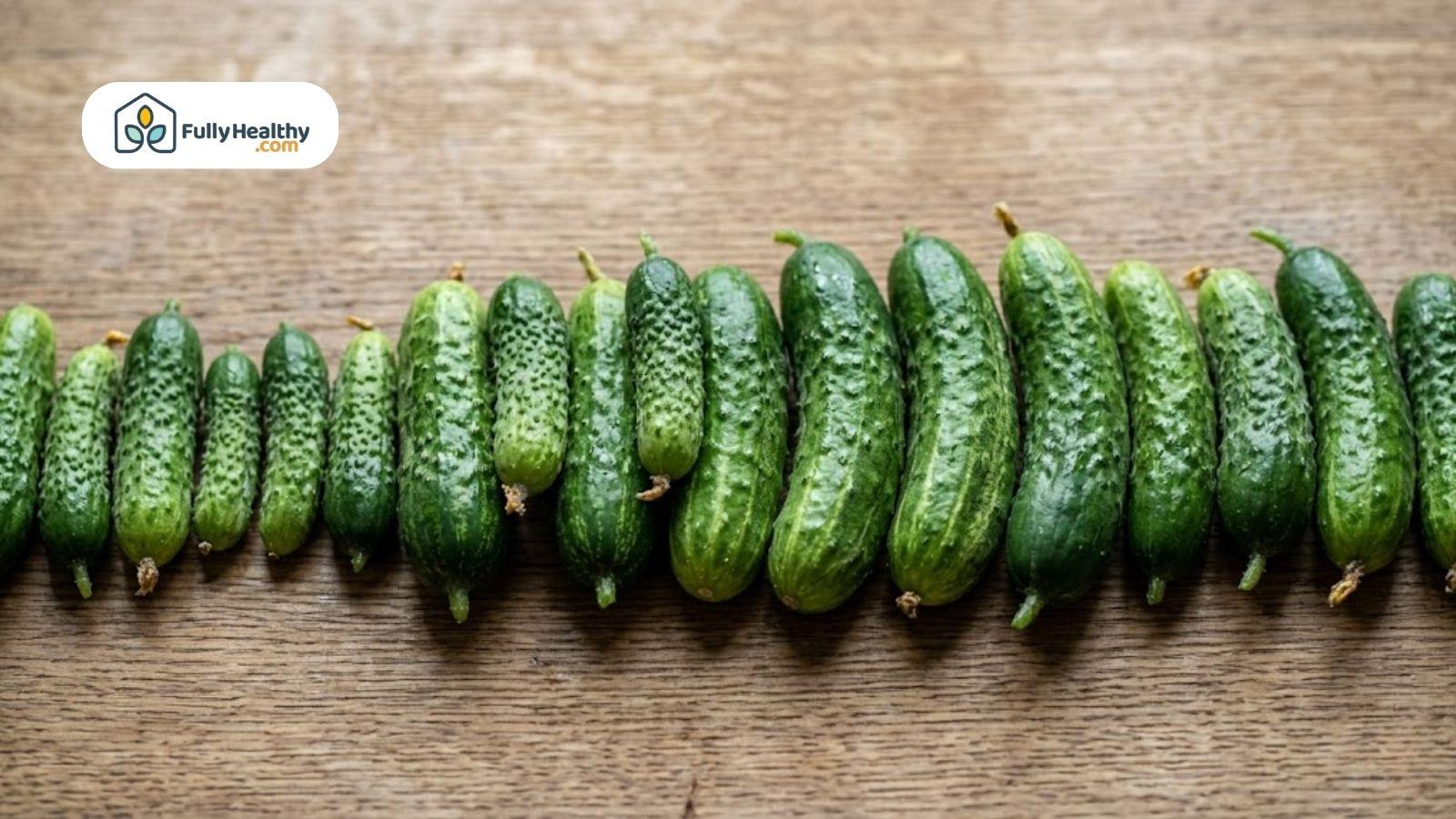 Row of cucumbers lined up on a rustic wooden surface.