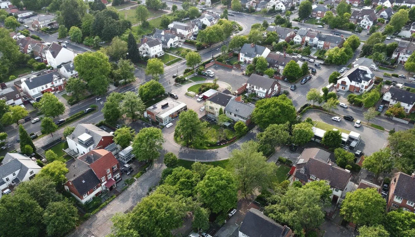 An aerial view of a residential neighborhood showcases various property types, including single-family homes and multi-unit buildings, with visible zoning distinctions. The image highlights the layout of streets and green spaces, providing insight into land information relevant for property files, resource consents, and local government official information.