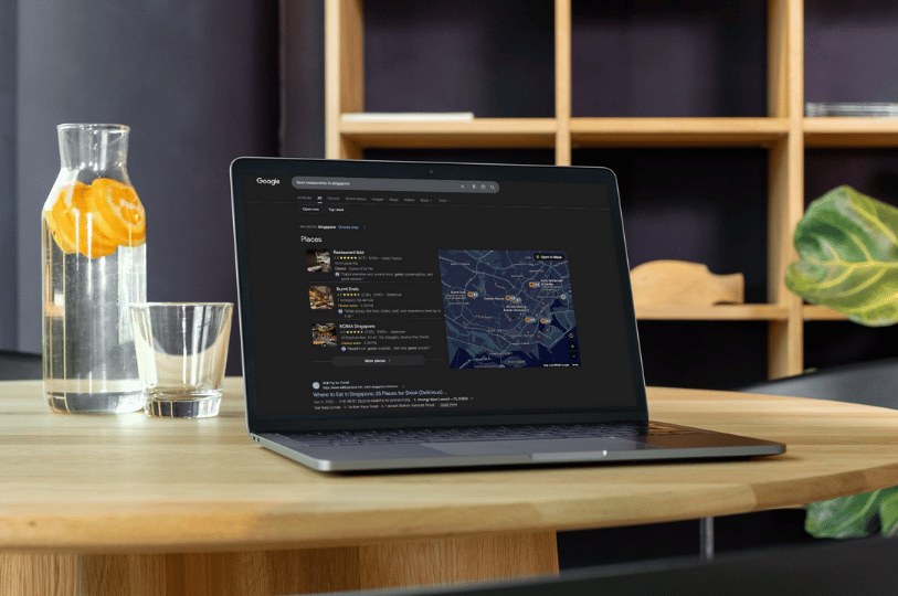A laptop on a wooden table displaying a Google "Places" search result for restaurants in Singapore with a map view. This illustrates the local pack and the importance of appearing in Google Maps for restaurant discovery.