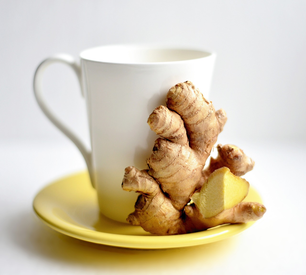 An image of ginger root on a saucer with a tea cup. 