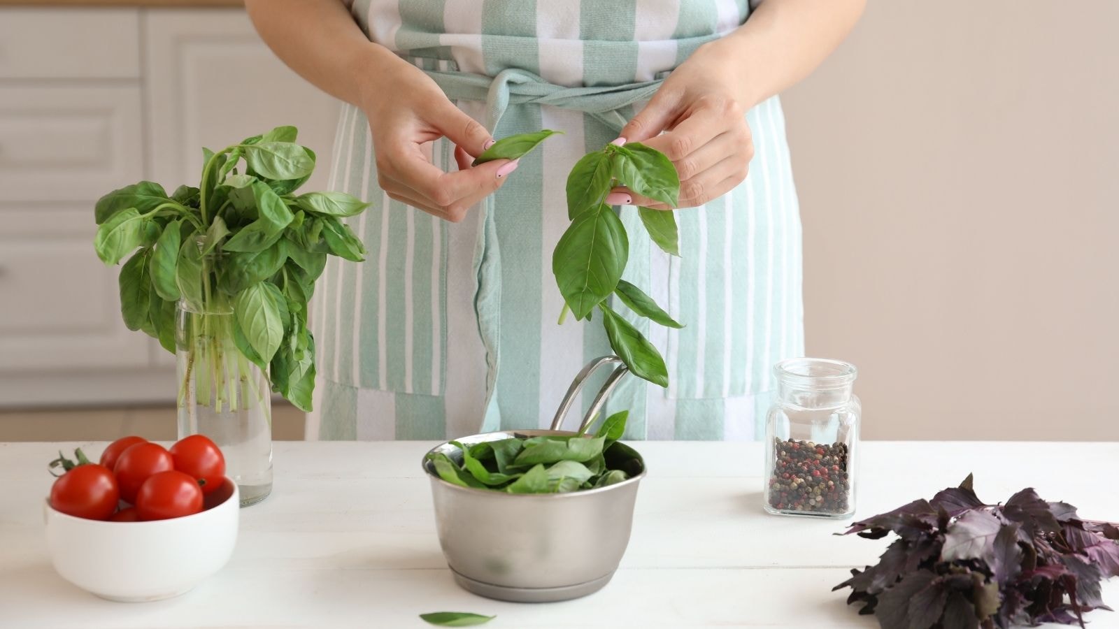 Person picking fresh basil leaves from a bunch on the counter before freezing