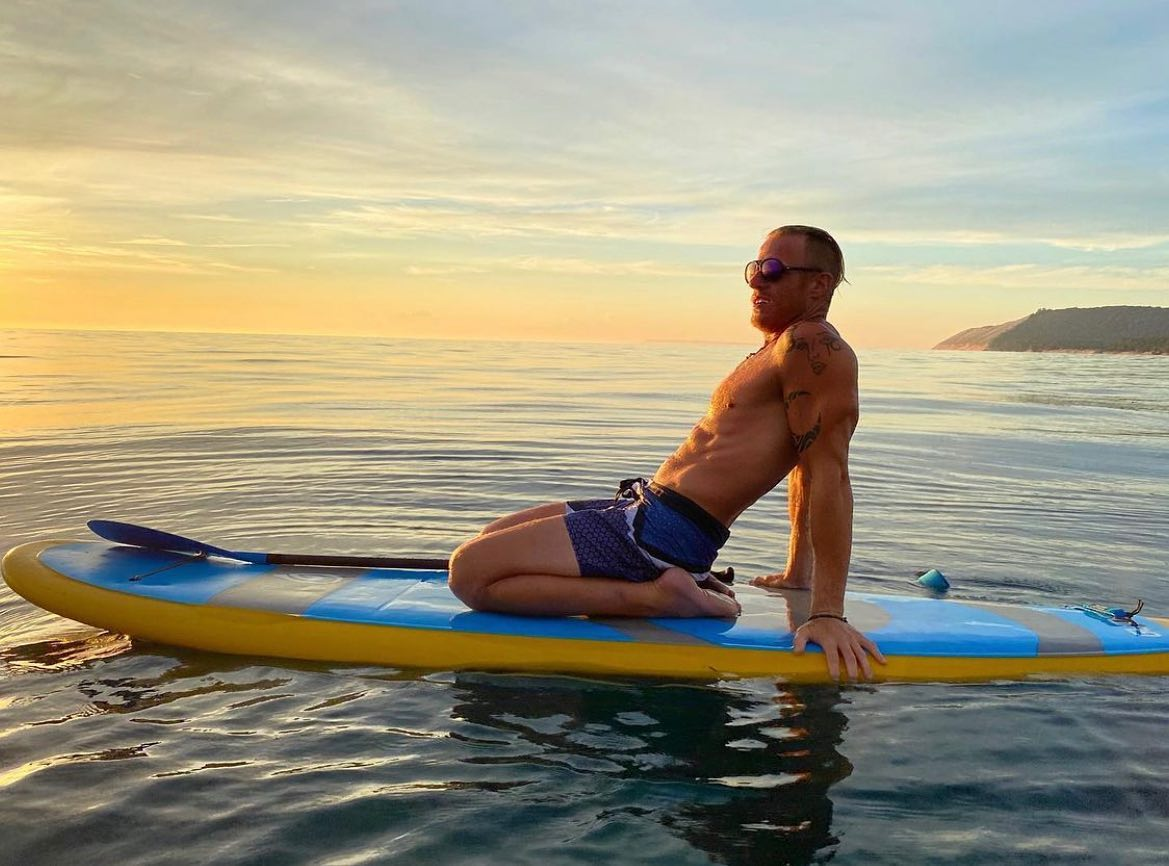 man kneeling on a paddle board