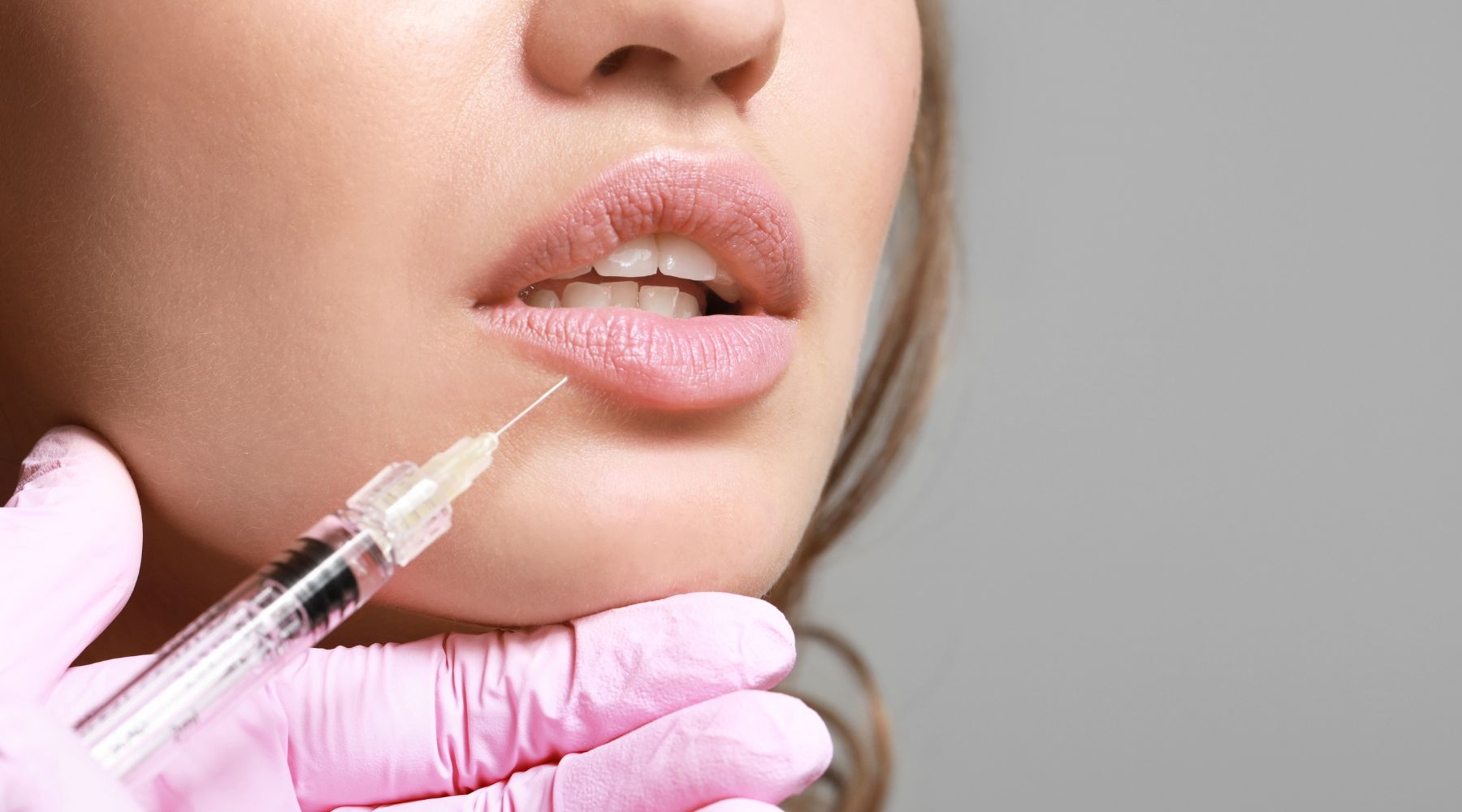 Close-up of a woman receiving a lip injection with a syringe.