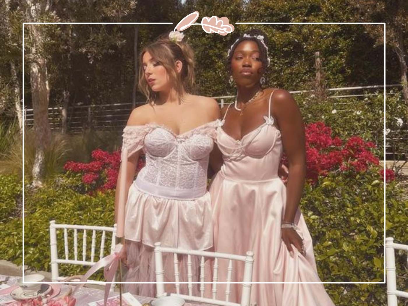 Two women in elegant dresses standing by a garden table, exuding elegance and confidence at an outdoor event.