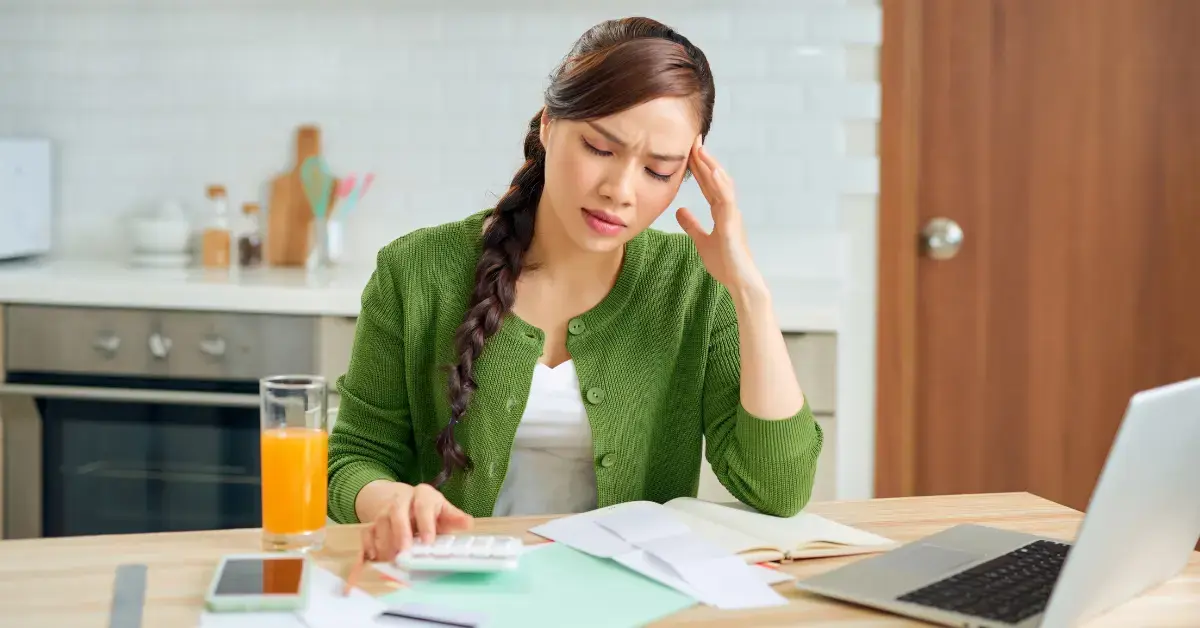 Woman reviewing an IRS notice and home papers at her table, worried about tax debt and asking can the IRS make you homeless.