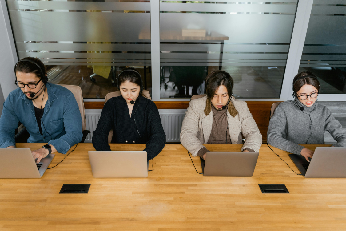 Filipino remote team members working with headsets and laptops in a shared office space
