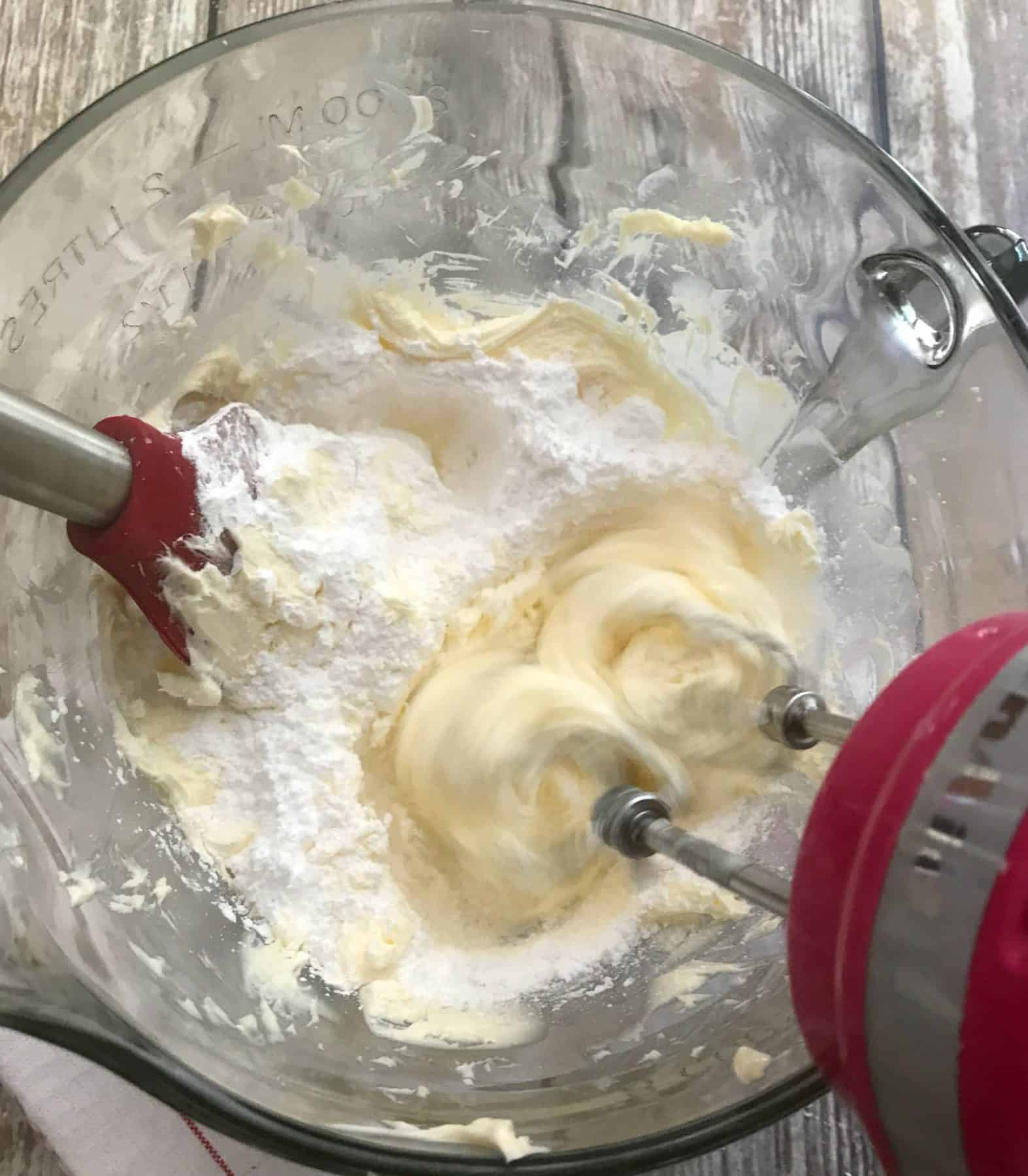 powdered sugar being mixed into mixing bowl with butter and shortening