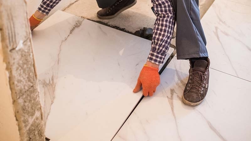 A man installing large ceramic floor tiles