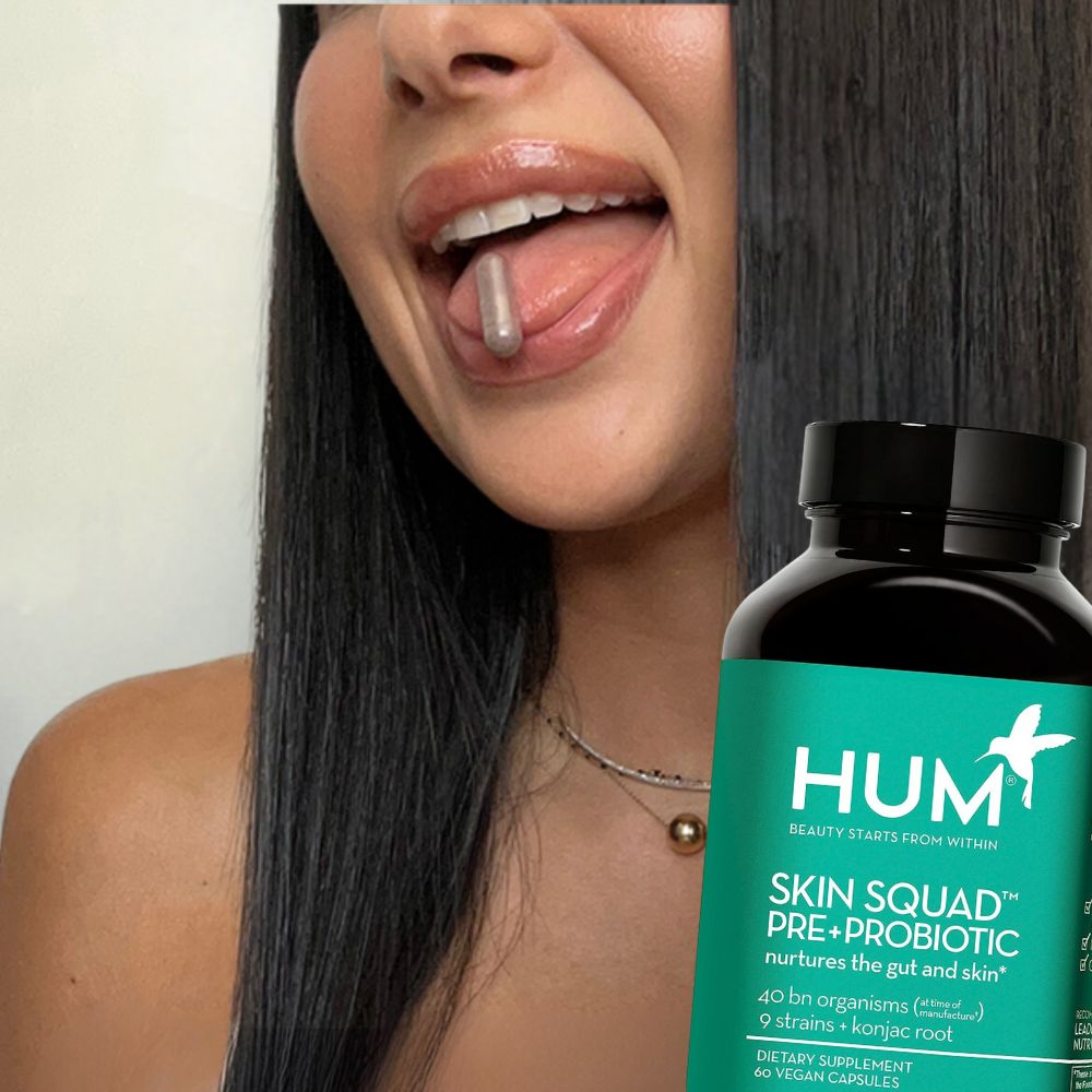 A woman taking two capsules of Hum Skin Squad Pre Probiotic Clear Skin Supplement