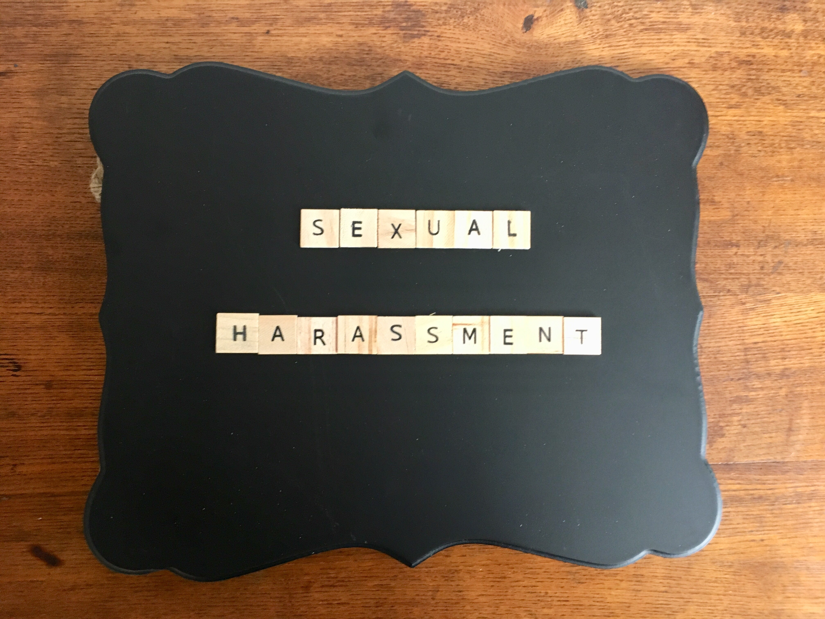 "The words 'SEXUAL HARASSMENT' starkly displayed on a wall, a raw reminder to address and eradicate such misconduct in the workplace."