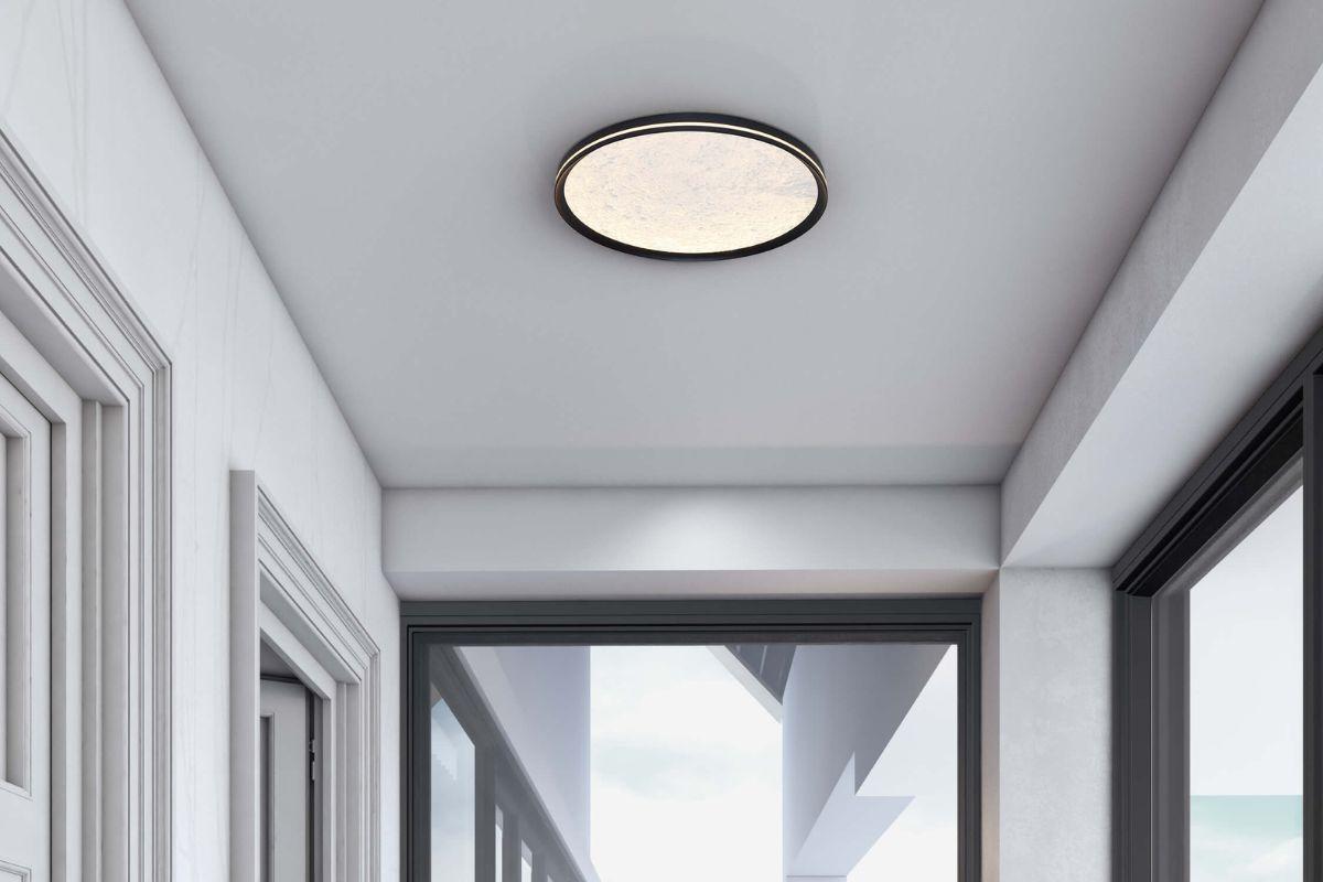 Large round flush mount ceiling light with black trim in a bright modern hallway