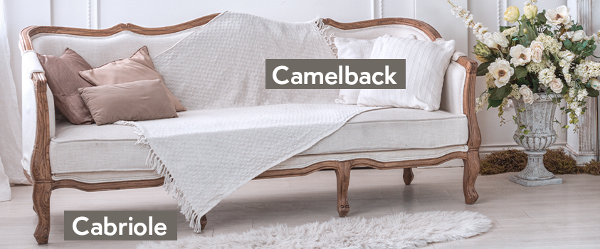 A traditional white and wood frame camelback sofa with cabriole legs.