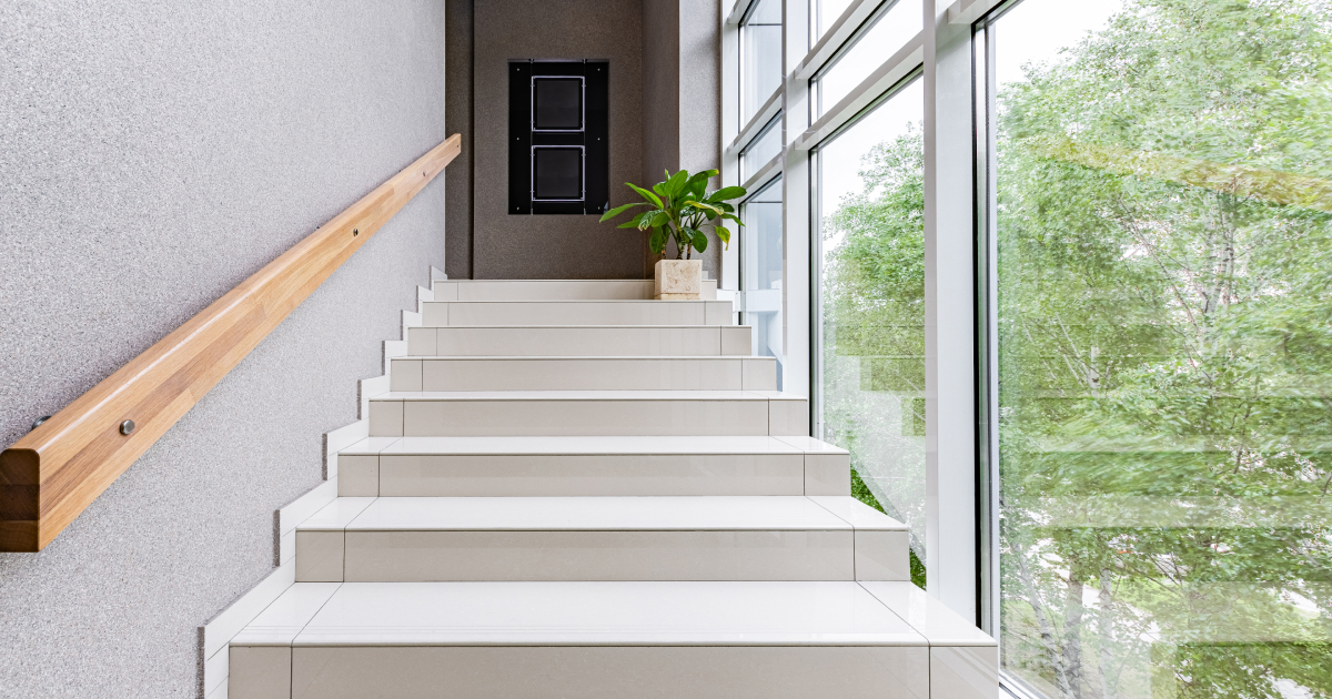 Een witte betonlook trap met een houten bruine trapleuning en witte trapwangen