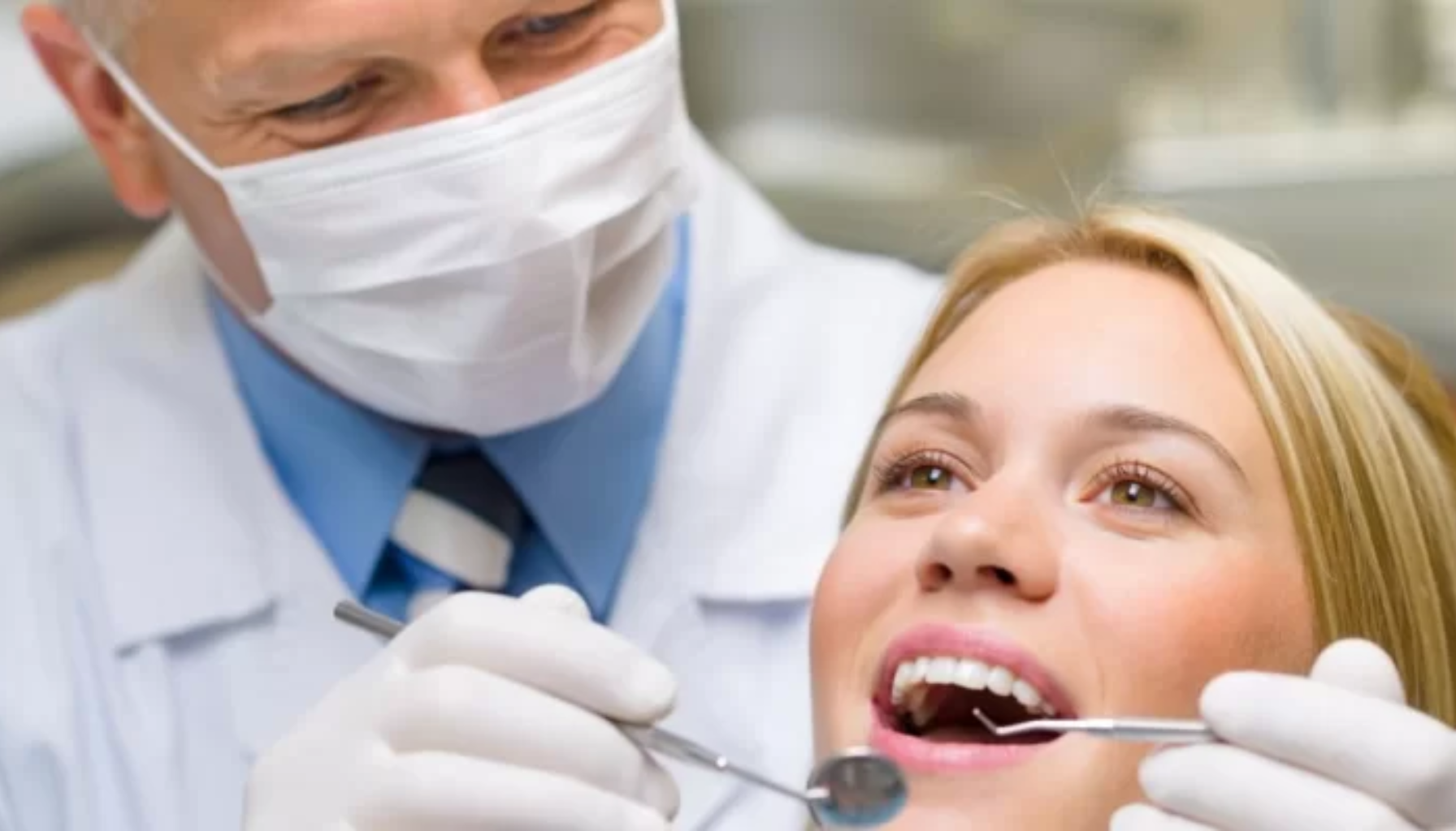 All-on-4: Tannløsningen Som Forandrer Livet Ditt På Én Dag 17 Alt-tekst (norsk): Tannlege med munnbind undersøker en kvinnelig pasients tenner med tannlegeinstrumenter under et rutinemessig besøk. Pasienten ser rolig og avslappet ut i tannlegestolen.