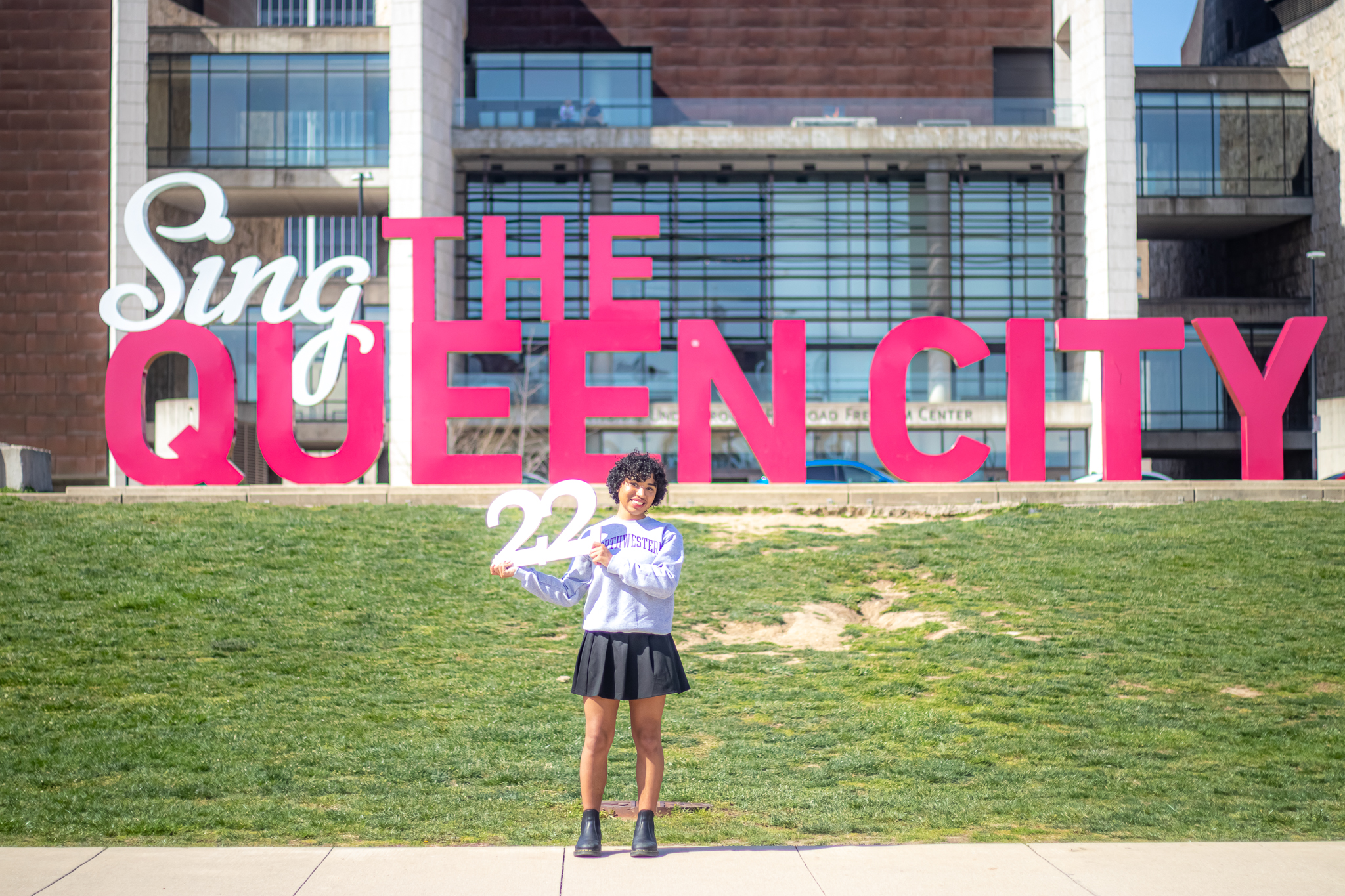 Senior photo ideas taken in a meaningful location make great senior picture options. 22 grad in front of a well-known sign like this one "Sing the Queen City."