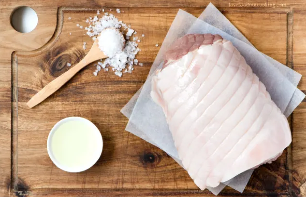 To achieve crispy crackling, pat dry the pork skin and make small criss-cross incisions. Oil and salt the pork rind generously before placing it in a hot oven to start the crisping process.