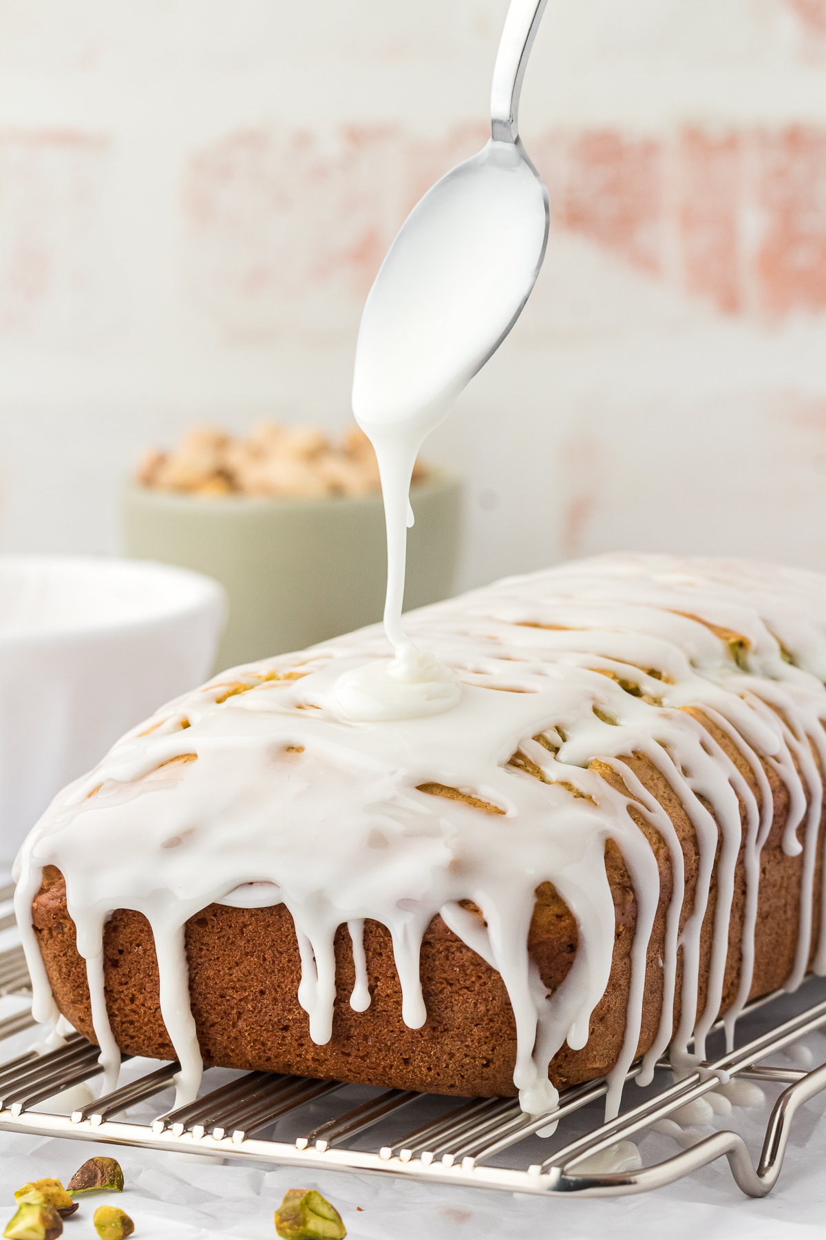 almond glaze drizzled on to pistachio quick bread with a spoon
