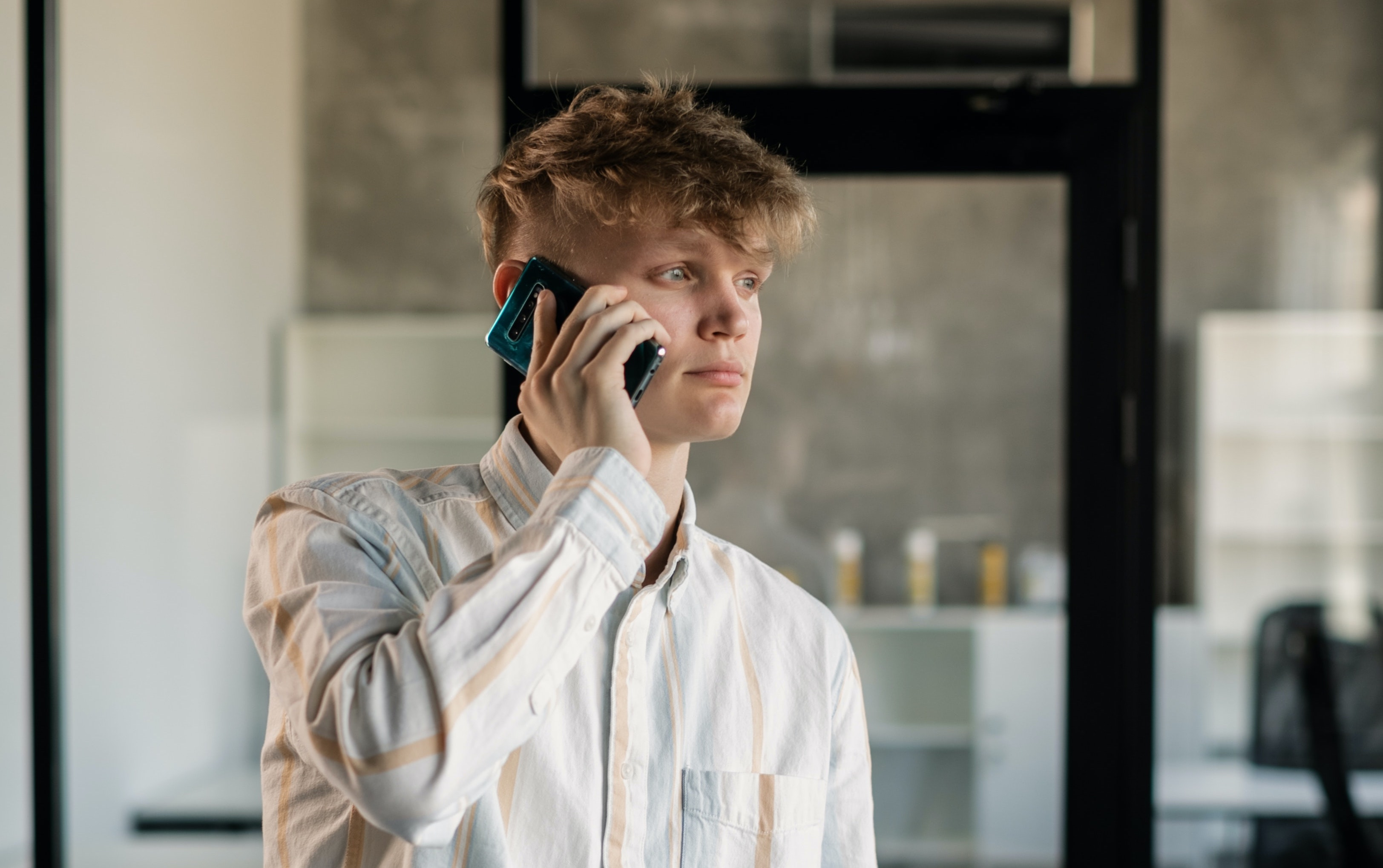 Man holding phone wearing a collared shirt