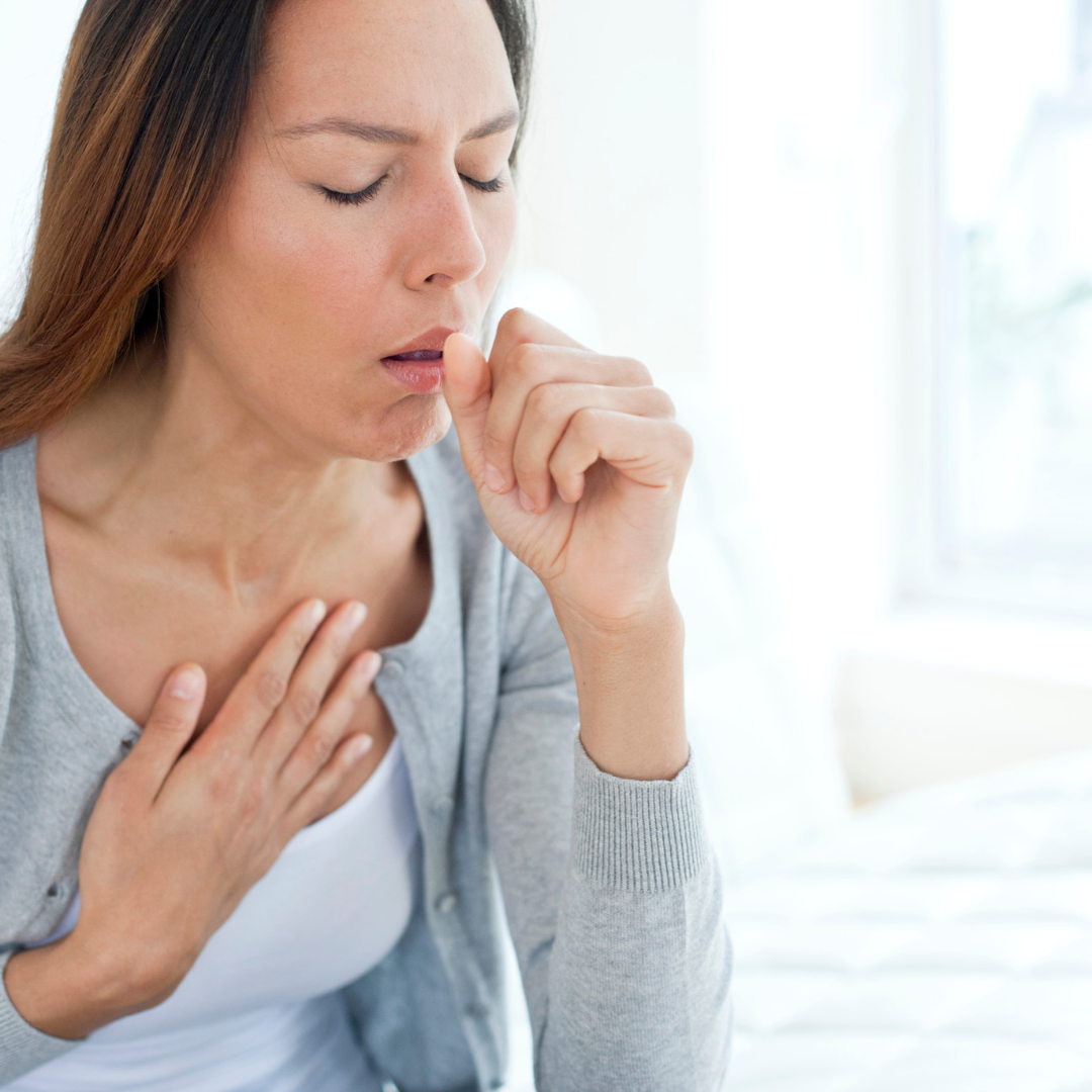 woman coughing into a closed fist