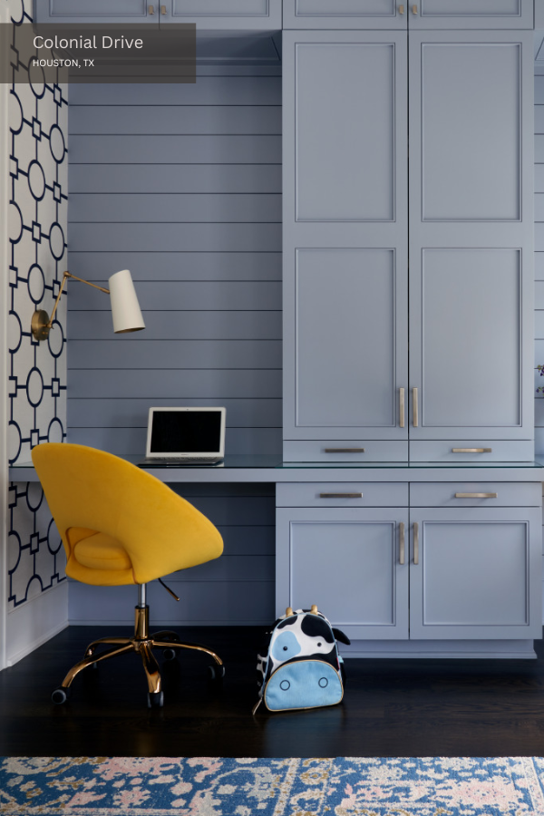 Pale blue millwork, bold geometric wallpaper, and a bright yellow desk chair in a child's study room