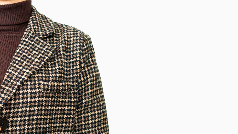 A close-up of a person wearing a plaid houndstooth coat