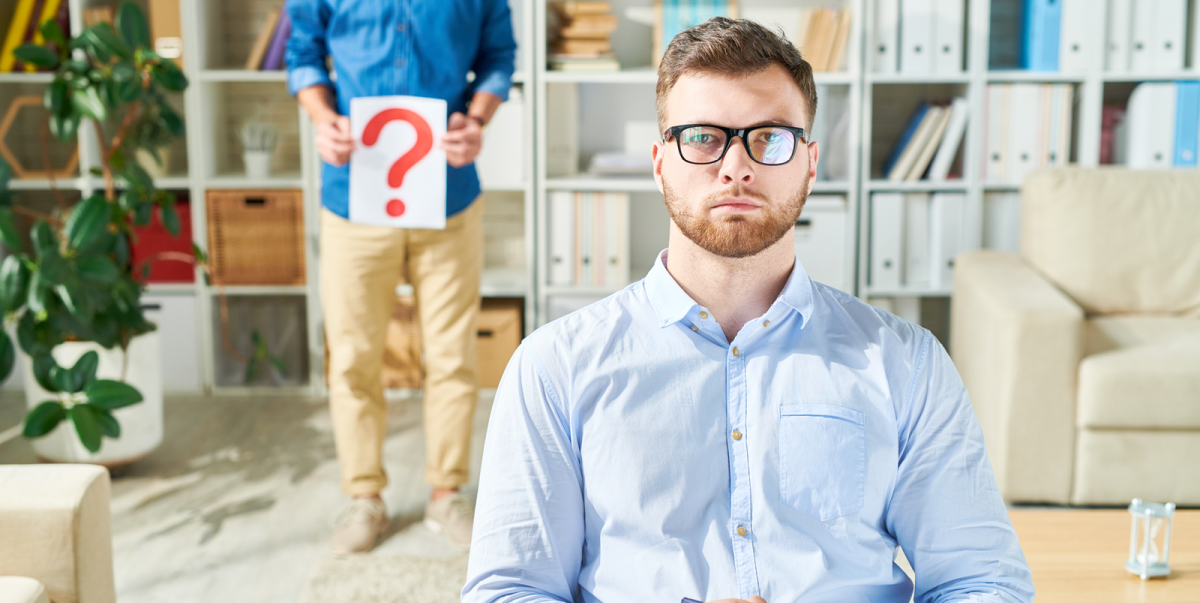 A compassionate therapist at GayCouplesTherapy.com in New York City assisting a gay man with his sexual concerns, as he holds a question mark symbol in front of his body, representing the journey of understanding and overcoming sexual issues in a supportive environment for gay couples.