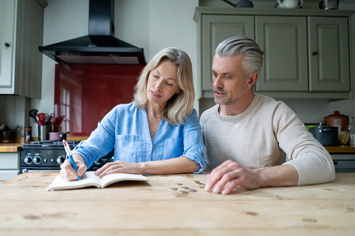 Lovely mature couple working on finances at the kitchen table. 