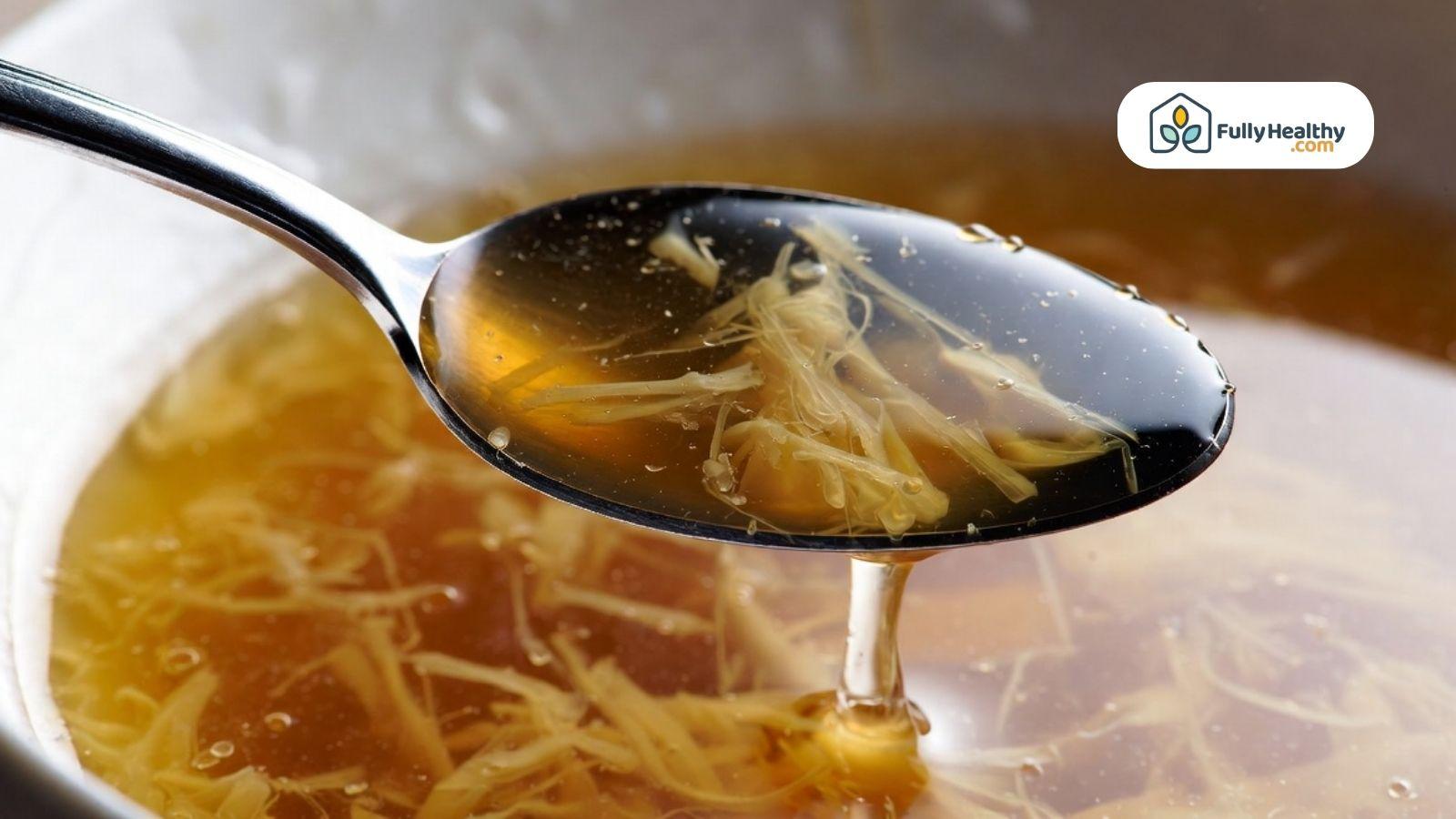 Spoon lifting rich broth showing gelatin strands and glossy texture.