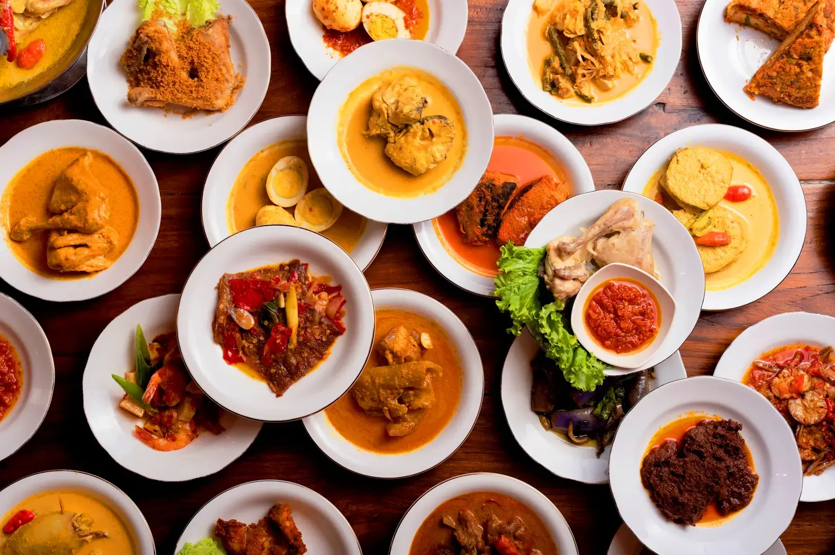 Indonesian food spread featuring traditional dishes, curries, sambal, vegetables and fried chicken