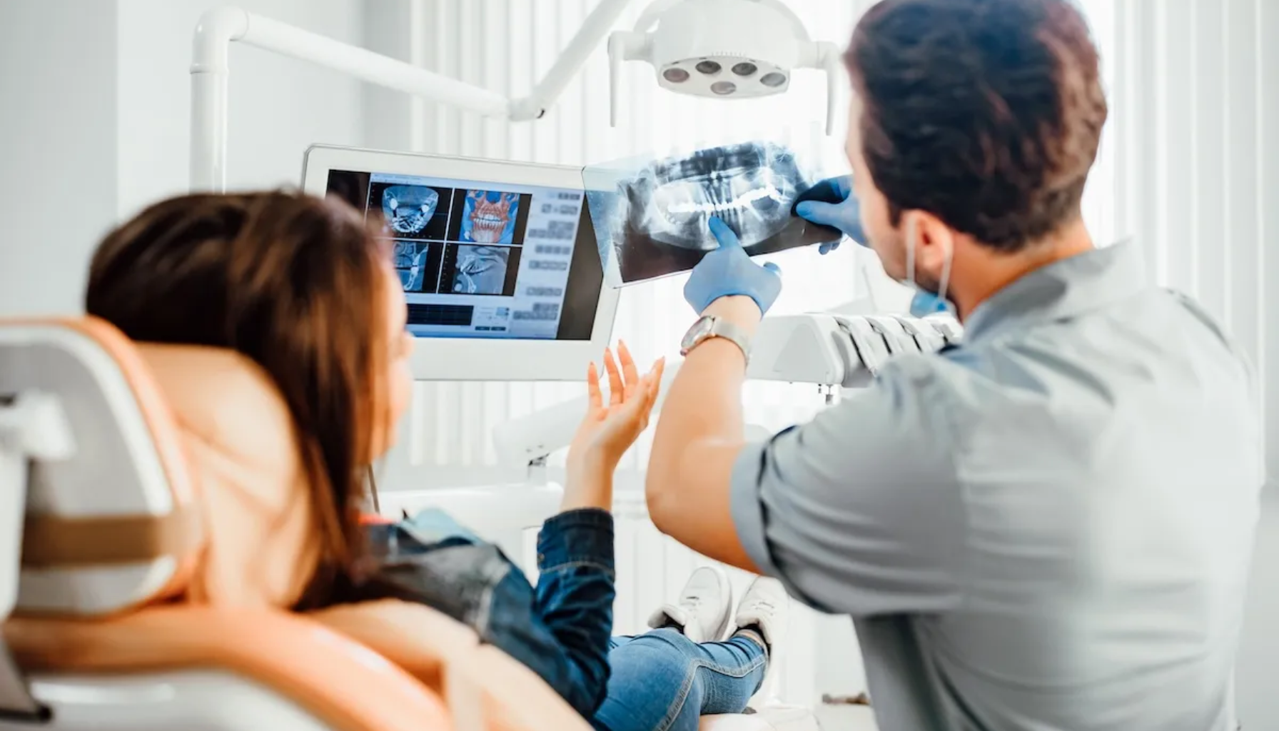 Privat tannlege: Når du vil ha tid, trygghet og skreddersydd oppfølging 7 Tannlege viser pasient røntgenbilde og forklarer funn mens hun ligger i stolen i moderne lys klinikk.
