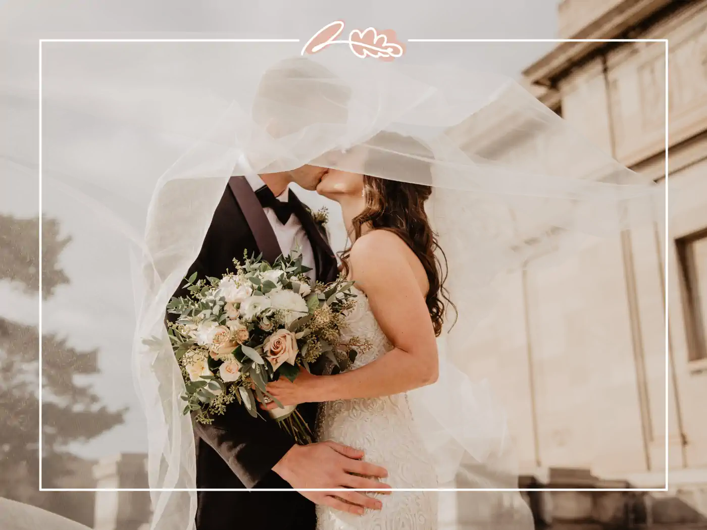 Bride and groom kissing under a veil, the bride holding a lush bouquet of flowers that includes garden roses. Fabulous Flowers & Gifts