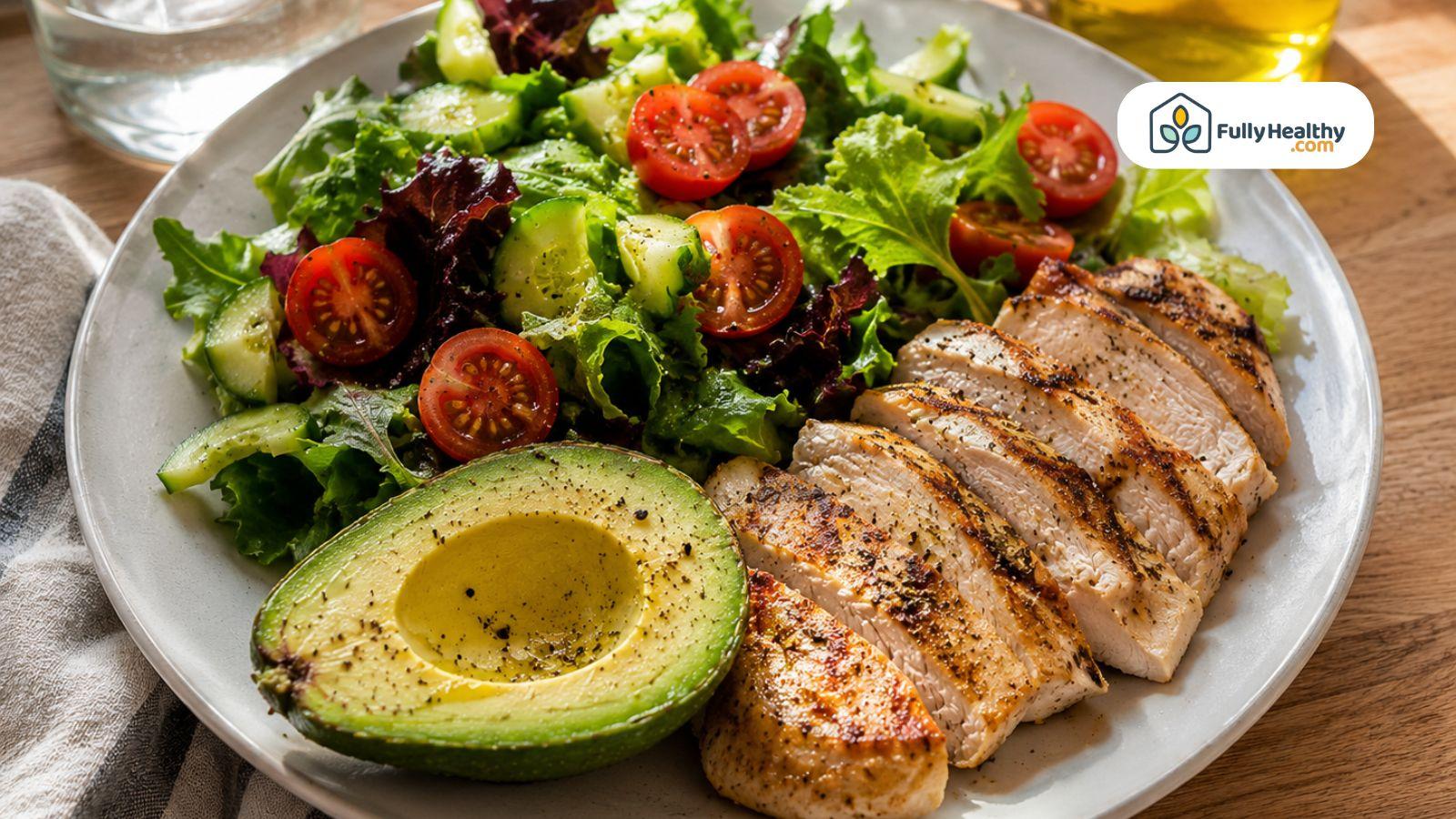 Grilled chicken salad with avocado and fresh vegetables on white plate