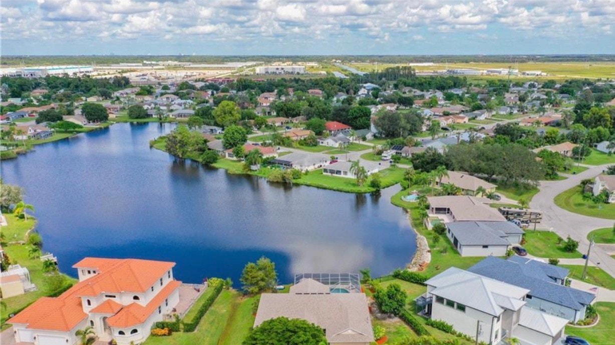 An aerial view of the San Carlos Park residential community in Fort Myers, FL, showcases tree-lined streets filled with single-family homes, many featuring private pools. This beautifully planned living area offers a desirable neighborhood atmosphere, perfect for enjoying the Florida paradise lifestyle.