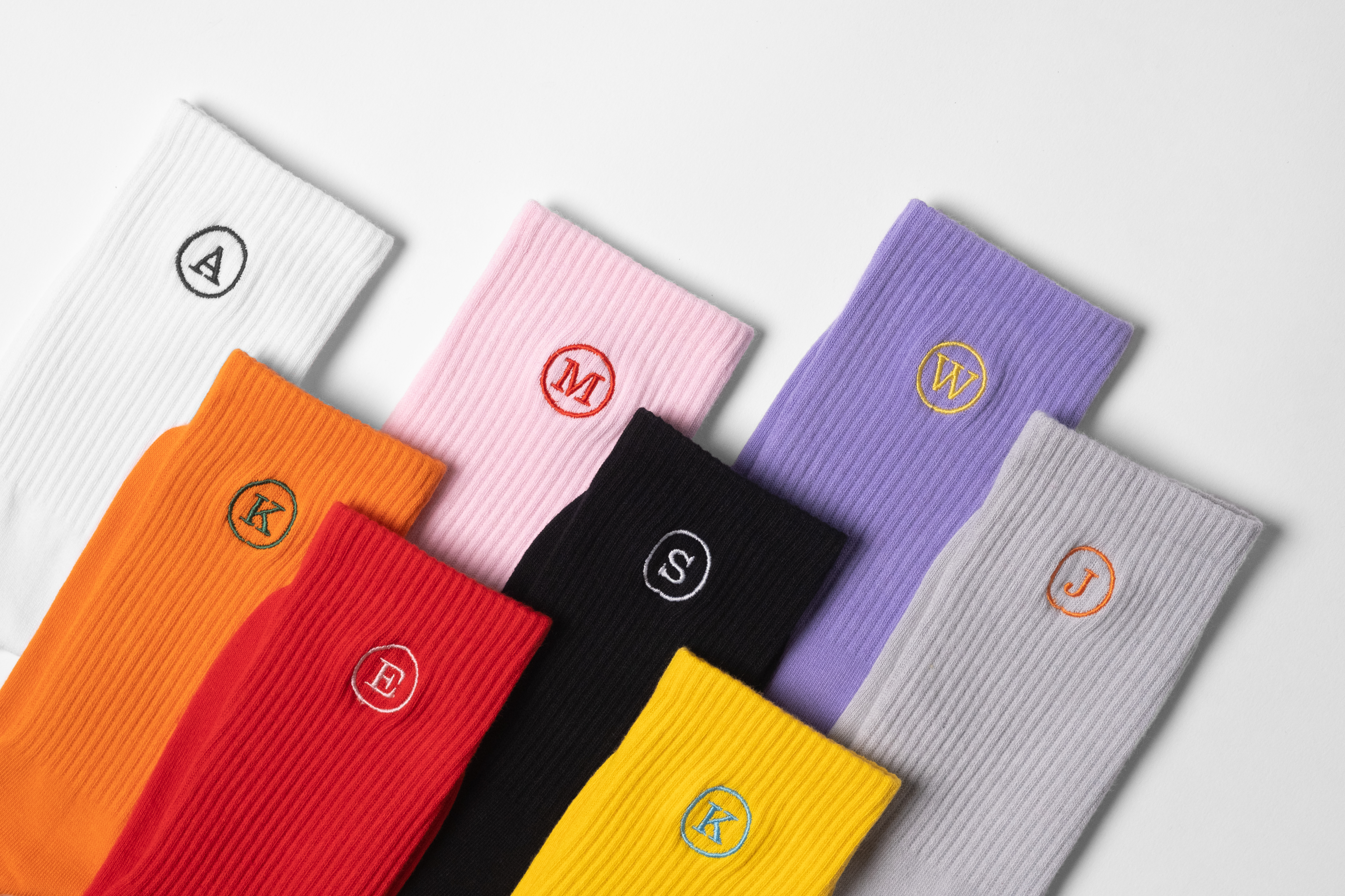 A colourful collection of mens customised crew socks with initials embroidery on each sock of the pair.