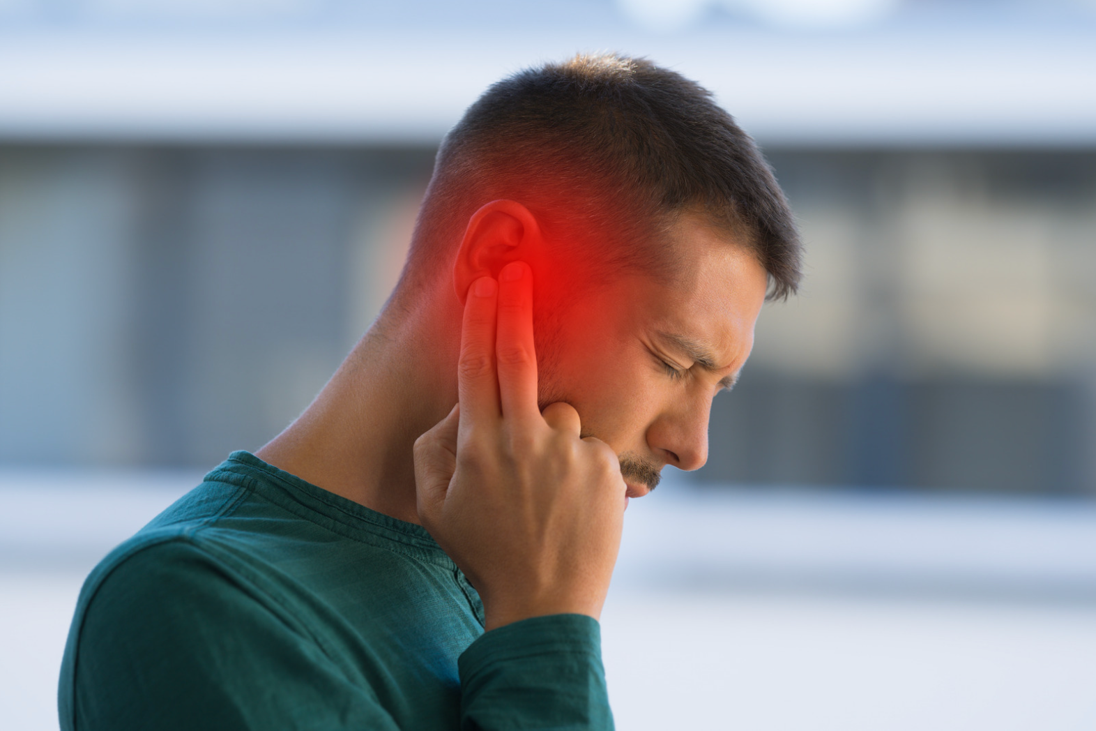 Young man feeling discomfort from tinnitus ringing sounds