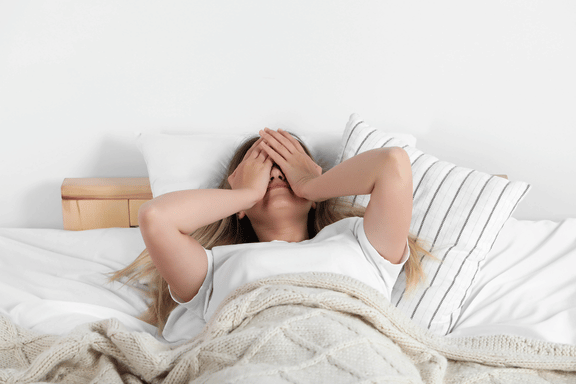 Woman covering face in frustration in bed unable to sleep wondering if she has a sleep disorder