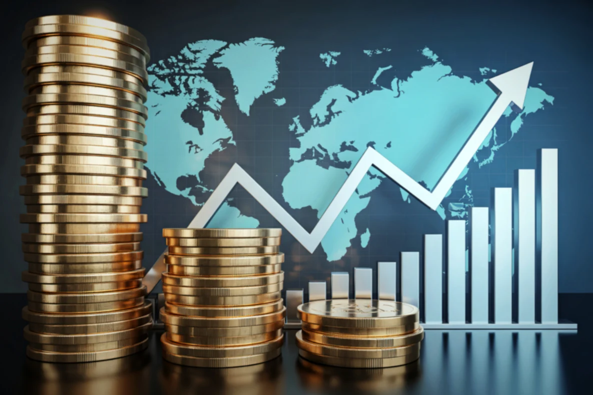 Stacks of gold coins in front of a blue world map with a white graph showing an upward trend.